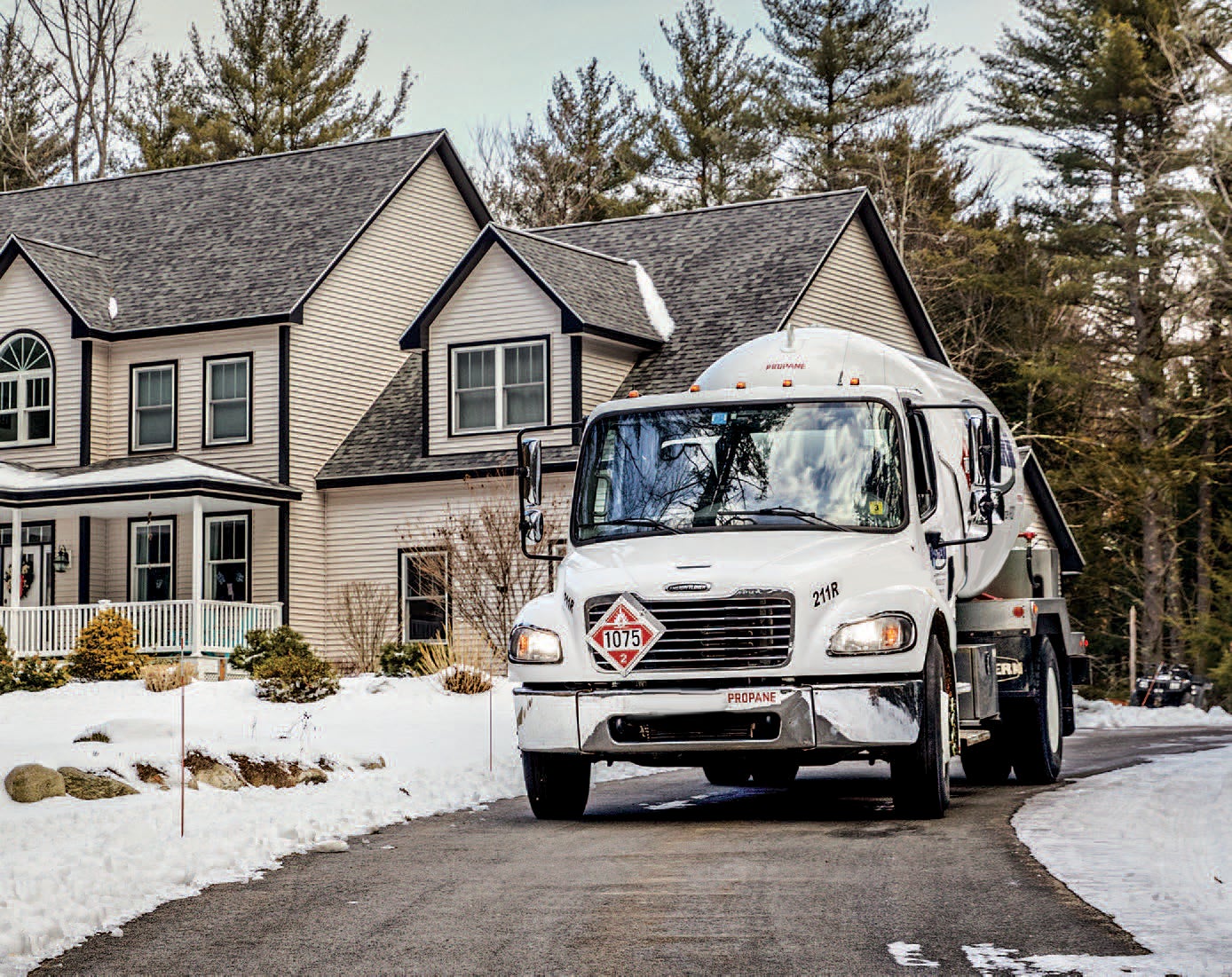 propane truck in driveway with tan house in background